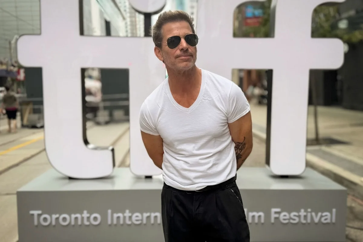 Imagem colorida de Zack Snyder no Festival de Toronto usando blusa branca e óculos de sol - Metrópoles