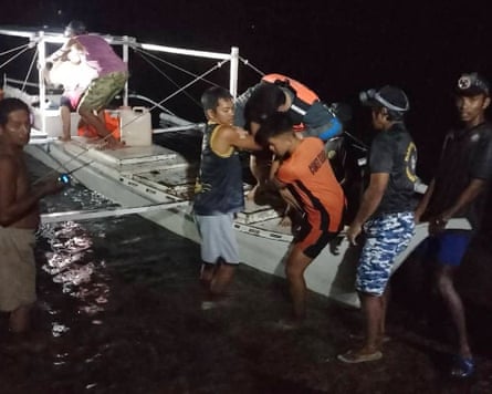 A survivor is assisted as he gets off a small boat after being rescued from the burning ferry