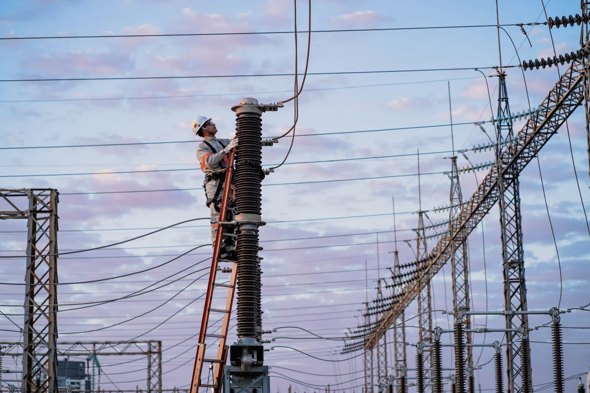 Fotografia colorida mostrando funcionário mexendo em poste de energia-Metrópoles