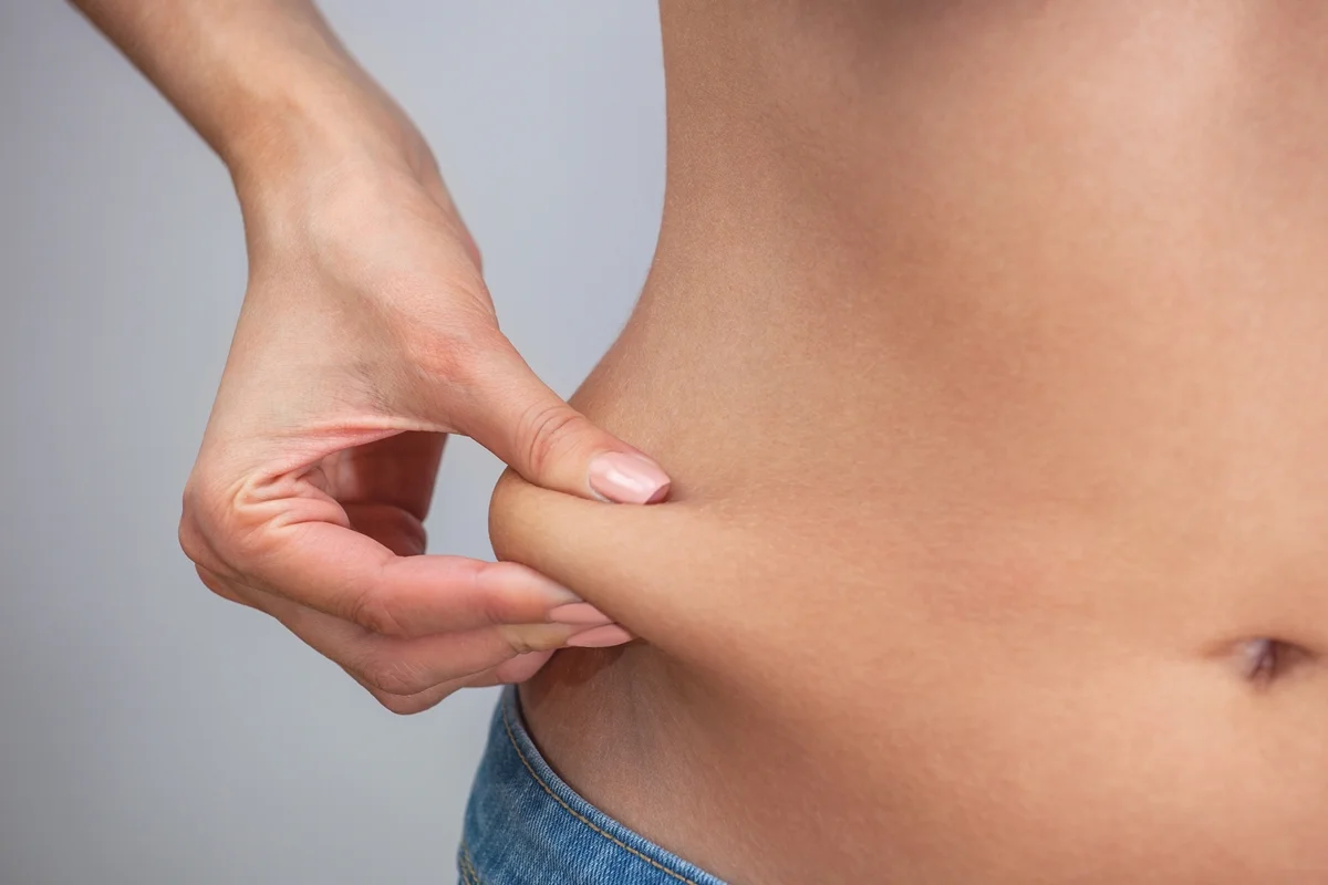 Foto colorida de mulher pegando na gordura localizada na barriga - Nutricionista explica o que é gordura visceral e por que é perigosa - Metrópoles