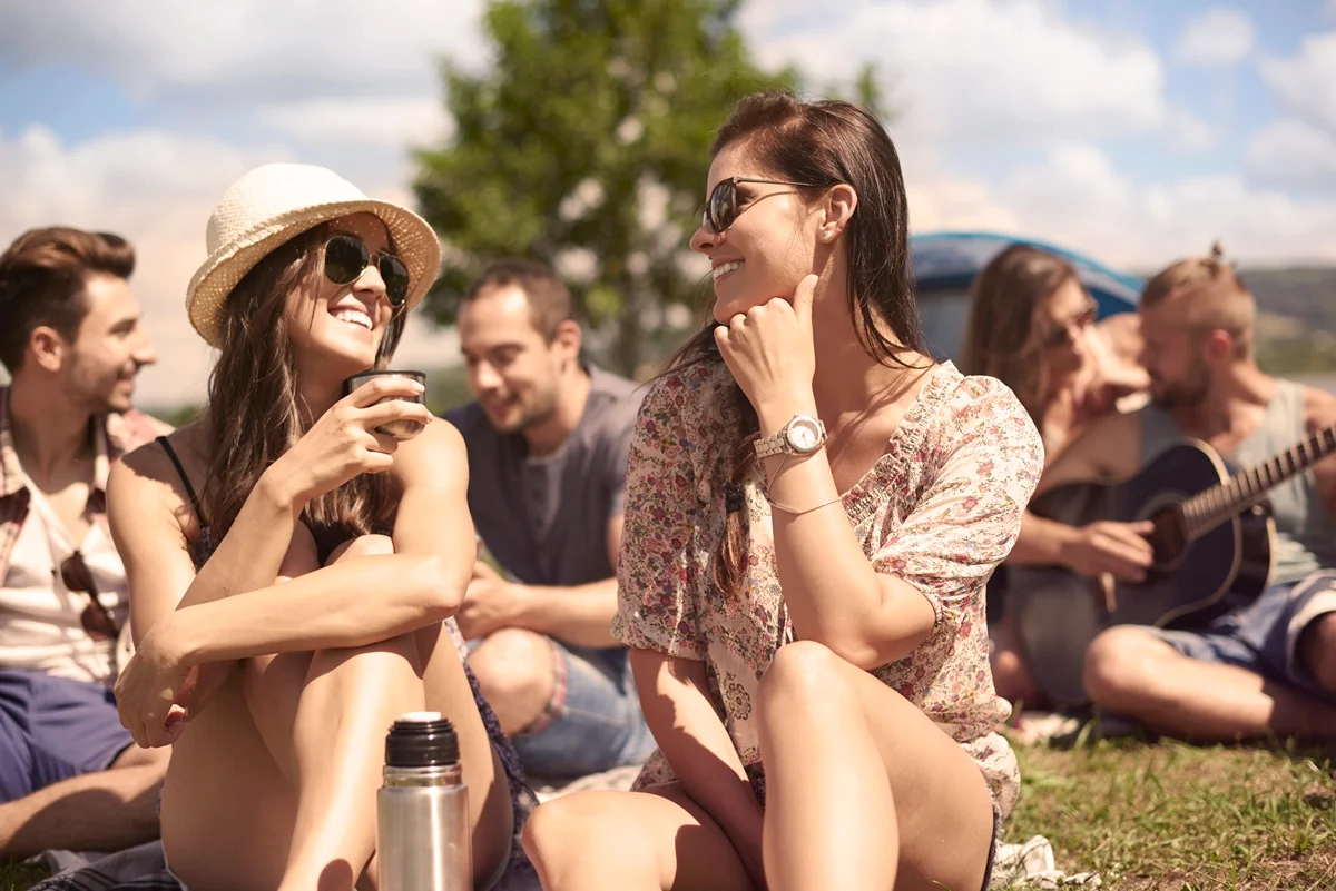 Jovens sentados em um gramado conversando. Eventos no sol, calor. Metrópoles